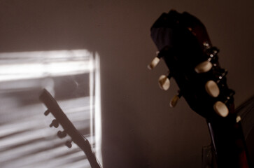 Close-up photo of an acoustic guitar with shadows. Guitar strings, neck, frets and body