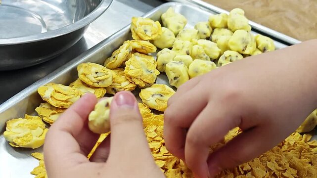 Hand-shaping homemade cornflake cookies in a bakery-style setting, creating a sweet snack that looks crispy, golden, and delicious.