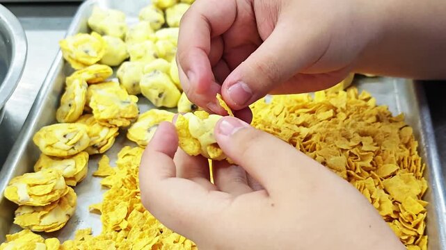 Hand-shaping homemade cornflake cookies in a bakery-style setting, creating a sweet snack that looks crispy, golden, and delicious.