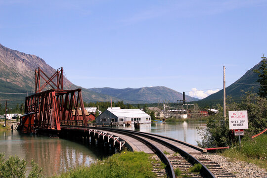 Red train bridge crossing over high waters in Carcross Yukon