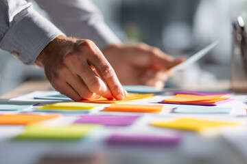 Fototapeta premium Close up of hands sorting colorful notes on a desk, symbolizing cognitive processing, decision making, and mental organization in a modern workspace.