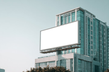 Large blank billboard mounted on a city rooftop against clear blue sky, providing copy space for outdoor advertising, branding, marketing campaigns, and urban business promotion.