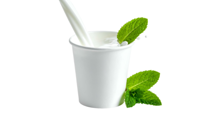 White cup filled with opaque liquid, mint leaves, stream of liquid pouring in