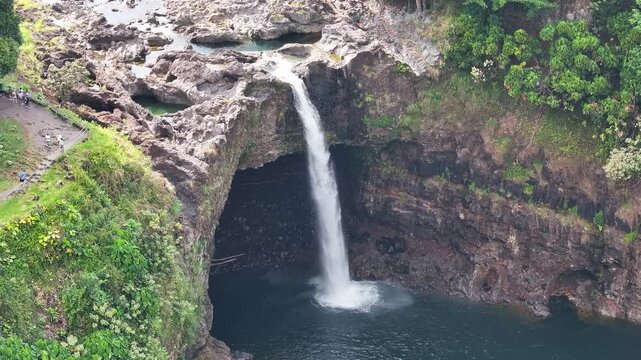 Aerial view of Rainbow Falls along Wailuku River waterfall landscape in Hilo Hawaii on the Big Island with lush greenery and water pool - 4K Drone