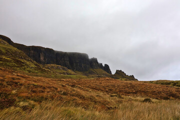 Dramatic cliffs and rugged landscape at The Quiraing, Isle of Skye, Scotland; steep rock formations and grassy slopes in autumn colours in the Scottish Highlands