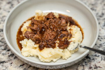 Roast beef and juice on mashed potatoes in a gray bowl. Delicious juicy dinner. 
