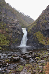 Fototapeta premium Lealt Falls on the Isle of Skye, dramatic waterfall plunging into deep gorge on the Trotternish Peninsula, scenic Highlands landscape with rugged cliffs and river views