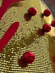 Christmas decoration - Multiple shiny red baubles hanging against a background of gold sequins.