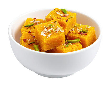 Golden Besan Burfi Cubes Topped with Nuts in a White Bowl