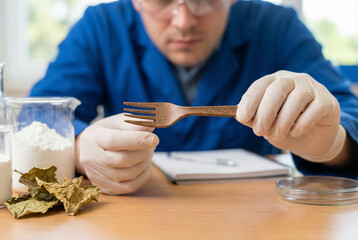 Scientist in lab inspecting biodegradable fork made from plant fibers, sustainable material research