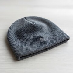 Stylish gray beanie resting on a simple white wooden surface close up
