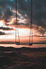 Empty swing set overlooking ocean at sunset image