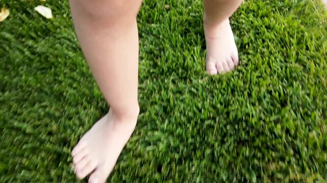 Feet of little girl while walking on grass in park or garden 4k