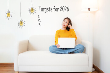 Targets for 2026 with young woman thinking plan new work.  People cheerful and happy new year with laptop on the sofa in living room.  Star together new year 2026