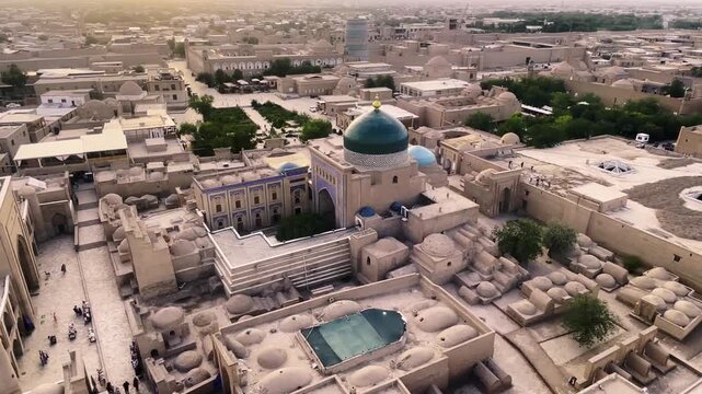 Aerial sunset detail of the historic monuments of Khiva. The shot lingers on the magnificent turquoise ceramic dome and the architectural complexes made of mudbrick