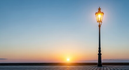 Obraz premium A street lamp with a glowing light against a clear blue sky at sunset.