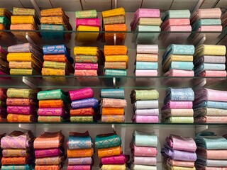 Traditional Indian silk sarees artfully arranged and showcased on shelves in a retail store. 