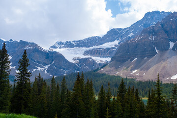 Obraz premium Mountains and trees in Banff Canada with snow on the peaks and clouds in the sky during daytime