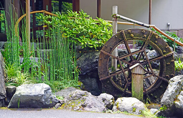 Rustic water wheel with moss and bamboo in a serene Japanese garden setting