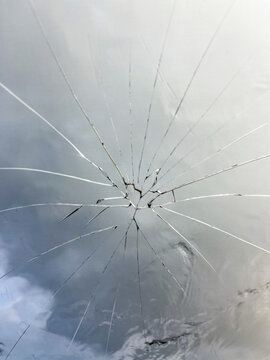 Shattered car window with radial crack pattern captured during travel incident, highlighting impact damage on vehicle glass and sudden roadside hazard encountered on journey.