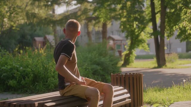 White Man Sitting On Bench Scanning Surroundings With Uneasy Glances, Daylight Park Scene With Trees And Path, Vigilant Posture And Wary Expressions Suggestive Of Social Anxiety And Hypervigilance
