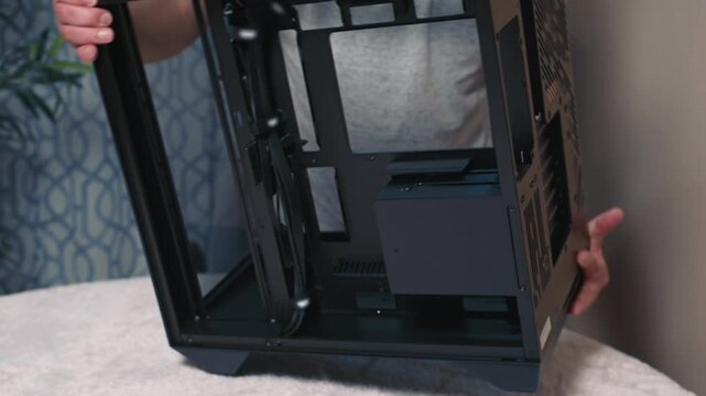 Man tilts and rotates computer case to inspect bottom and side sections