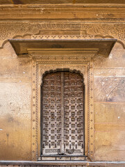 Obraz premium Close-up of an ornate carved doorway at Patwon Ki Haveli in Jaisalmer, Rajasthan. Traditional sandstone architecture with detailed patterns and antique wooden door design.