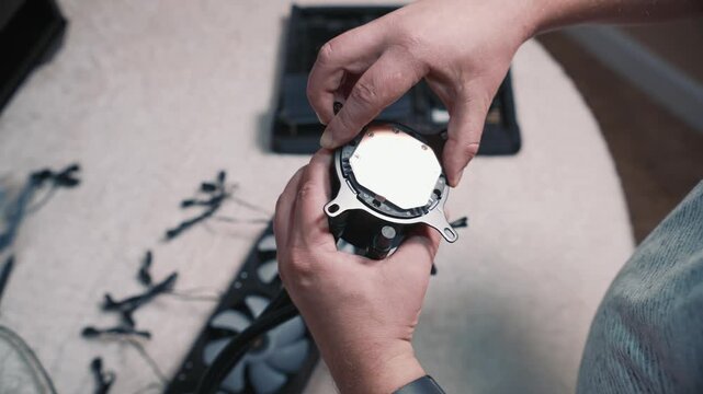 Man carefully peels off protective film from the copper base of a CPU water block before installing the liquid cooling system onto the processor