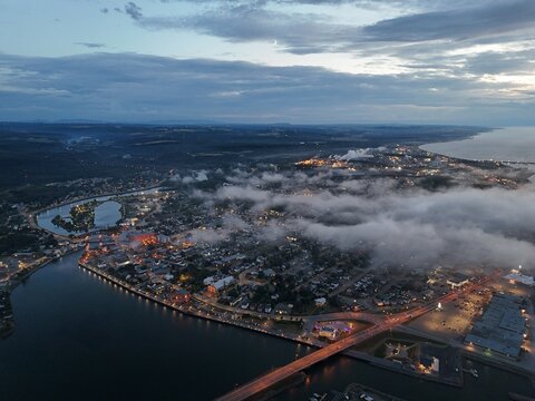 Aerial view of Matane city at dusk with river, fog, low clouds and city lights along St Lawrence River, Quebec, Canada. g.