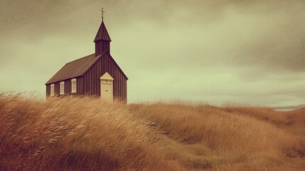 A small wooden church is set in a field of tall grass. The structure features a pointed roof and a steeple. The sky is overcast giving a muted light to the scene.