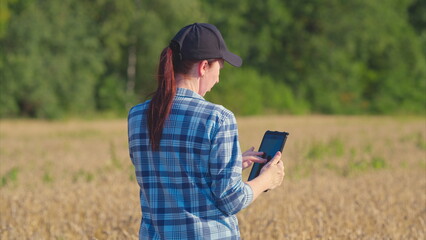 A Woman Happily Engaged in Using a HighTech Tablet in a Scenic Field on a Bright and Sunny Day