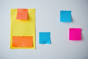 Fototapeta premium Colorful sticky notes on a white background are on the left, with space for text on the right. The photo was taken under spotlight lighting.