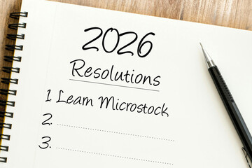 Handwritten 2026 Resolutions list in a spiral notebook with Learn Microstock as the first goal and a pen.