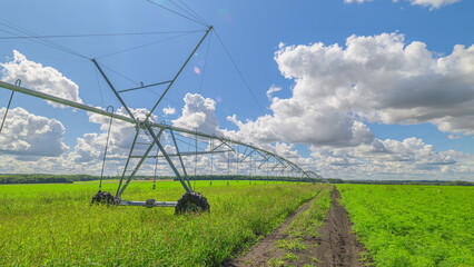 The irrigation system works efficiently in lush green fields under a bright blue sky