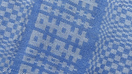 High angle close up of blue traditional Indonesian batik fabric with white floral geometric patterns.