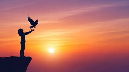 Silhouette of a person releasing a bird into a vibrant sunset sky from a cliff edge.