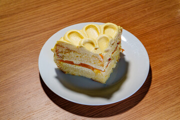 A Luscious Slice of Layered Cake with Ornate Yellow Frosting and Orange Fruit Filling Served on a...