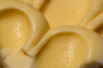 Abstract close-up of a creamy yellow dessert, revealing luxurious swirls and smooth texture with...