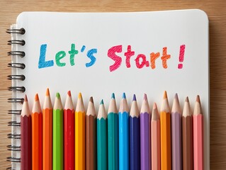 カラフルな色鉛筆とノートに書かれたLets Startの文字が新しい挑戦の始まりを感じさせるイメージ