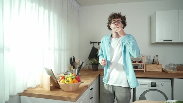 Happy father move to music while cooking food and prepare lunch at modern kitchen. Active dad dancing to song while making healthy food or salad surrounded with vegetable and kitchenware. Pedagogy.