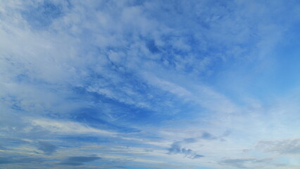 A vast and expansive sky adorned with intricate cloud patterns, leading to a tranquil blue horizon
