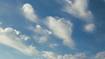 Witness the stunning beauty of the sky adorned with wispy clouds against a blue background