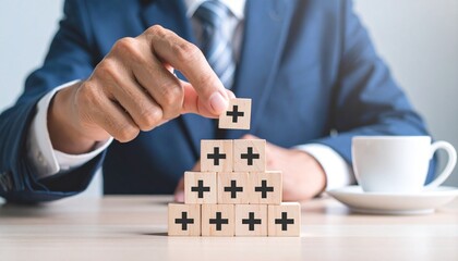 Business growth pyramid, person in suit placing wooden block with plus sign, strategic planning and achievement.