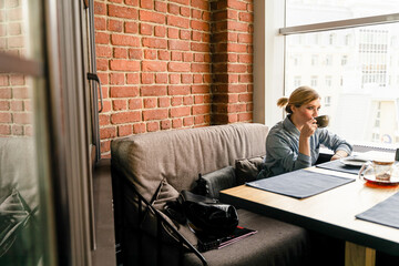 A girl is sitting at a table drinking a cup of coffee