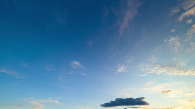Wide blue sky at sunset, scattered clouds tinged with pink and gold, soft gradient from azure to indigo, peaceful horizon, cinematic atmospheric texture suggesting gentle motion