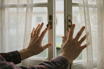 Hands Opening a Window with Sheer Curtains in Soft Morning Light