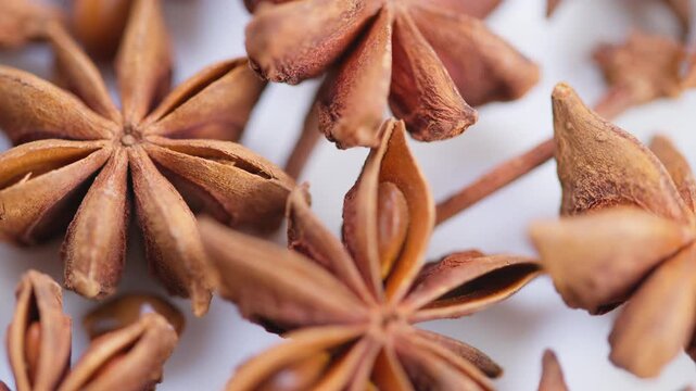 Star anise details, Detailed view of aromatic star anise on white surface, Focus on textured star anise pods emphasizing geometric seed patterns and rustic presentation