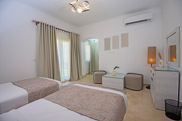 Interior design decor furnishing of luxury show home bedroom showing furniture and twin beds with balcony terrace