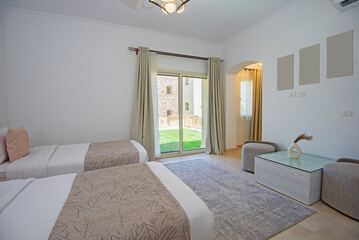 Interior design decor furnishing of luxury show home bedroom showing furniture and twin beds with balcony terrace