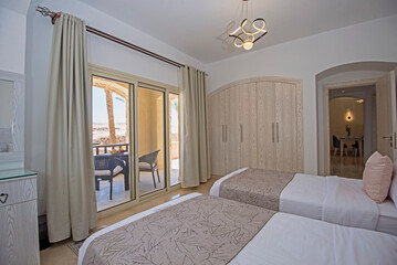 Interior design decor furnishing of luxury show home bedroom showing furniture and twin beds with balcony terrace